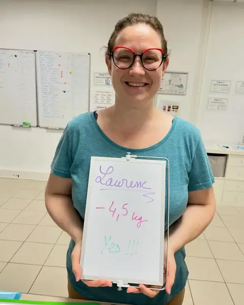 Au club, une membre ravie brandit son ardoise de bilan